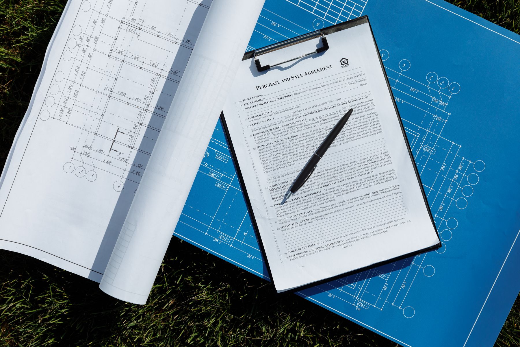 Construction contract on a clipboard beside architectural blueprints